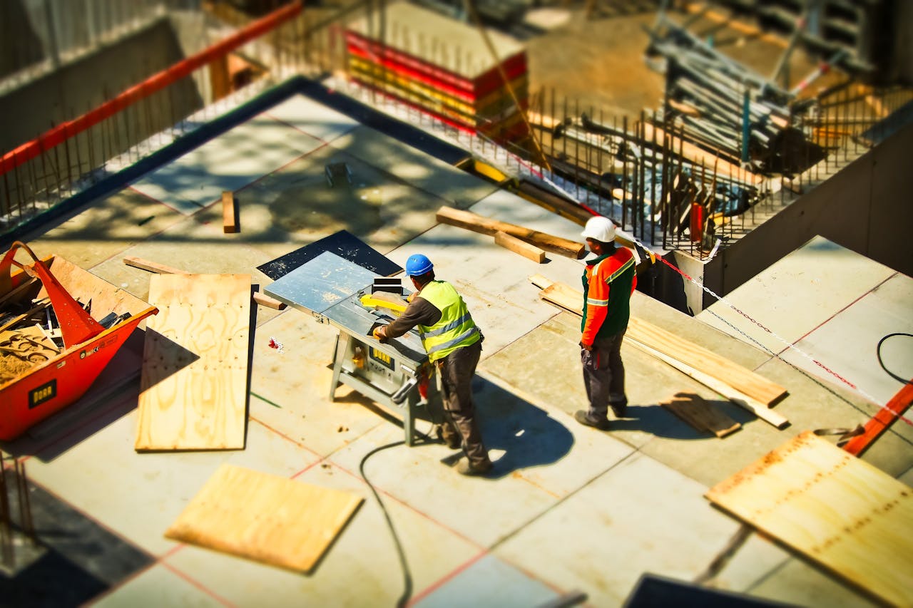 Home Construction workers engaging in tasks at an outdoor building site with safety hats and equipment.