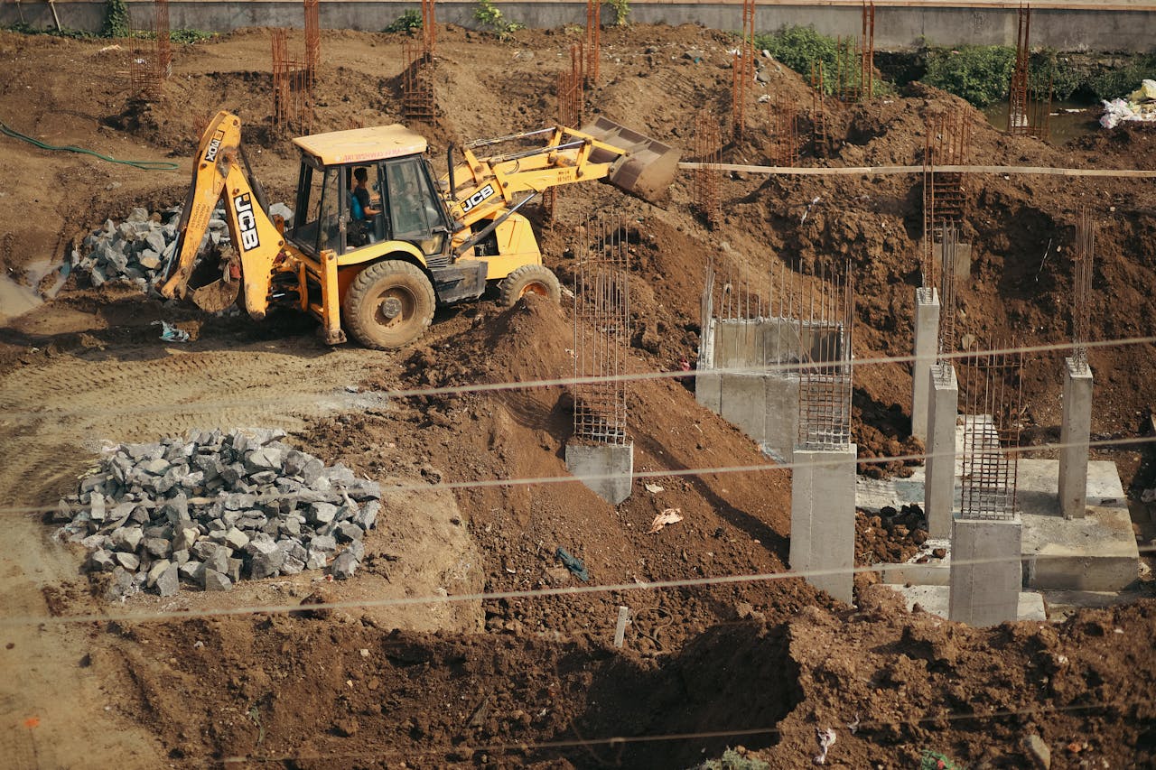 A bulldozer moves soil at a busy construction site, surrounded by piles of gravel and concrete structures.