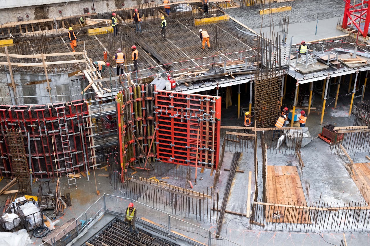 Home Industrial construction site with workers in high visibility clothing at a steel framework structure.