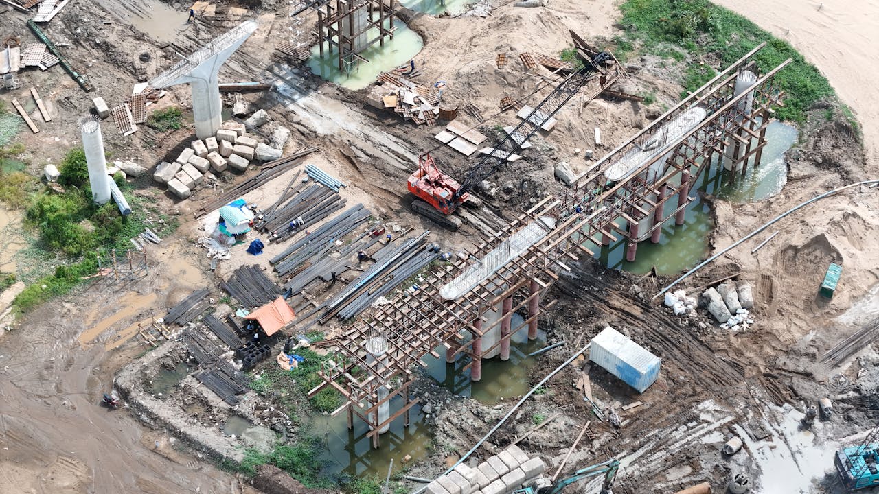 Home Aerial shot showcasing bridge construction with cranes and materials on site.