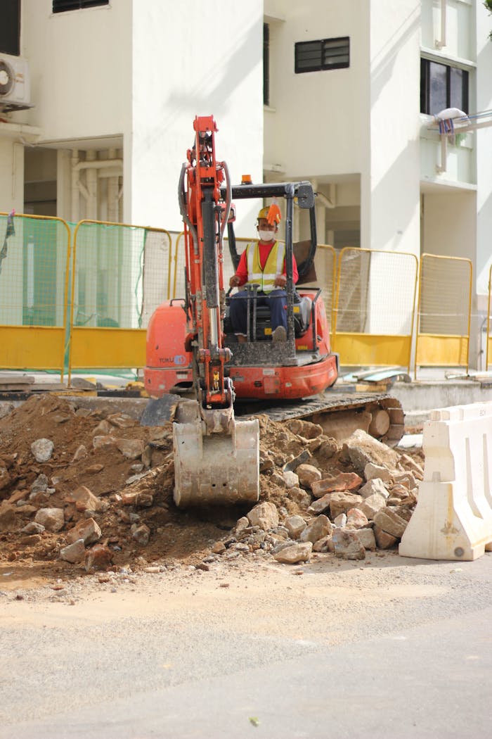 gallery-05 A construction worker operates a backhoe during a building project in an urban area.