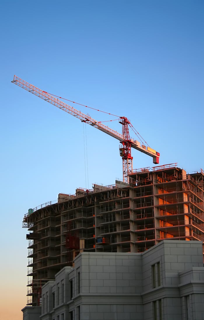 gallery-04 Tower crane on a high-rise building under construction at sunset, showcasing modern urban development.